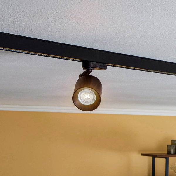 Bronzefarbener Strahler an einem schwarzen Schienensystem, an der Decke montiert.