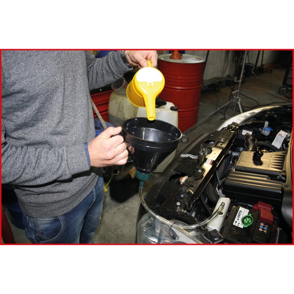 Eine Person gießt Flüssigkeit mit einem Einfülltrichter in einen Automotor.