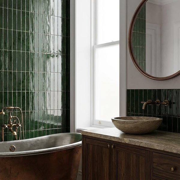 Modernes Badezimmer mit dunkelgrünen Wandfliesen, einer kupferfarbenen freistehenden Badewanne und einem Waschtisch mit Natursteinwaschbecken.