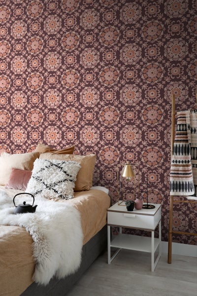 Schlafzimmer mit gemusterter Tapete, Bett, Nachttisch und Dekoartikeln