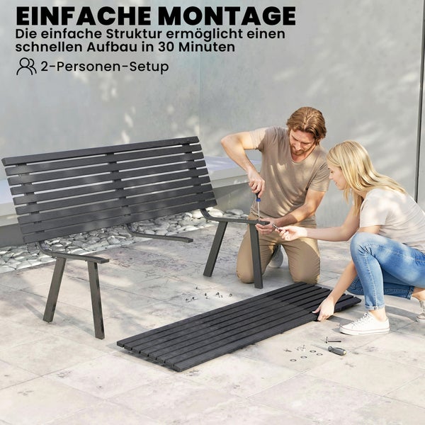 Zwei Personen montieren eine Gartenbank aus Holzlatten und Metall auf einer hellen Terrasse. Montagezeit circa 30 Minuten.