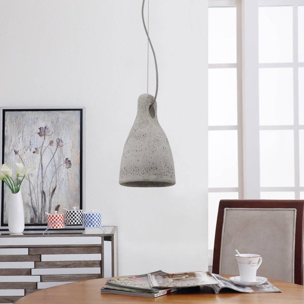 Hängeleuchte aus Beton in Glockenform über einem Holztisch in einem hellen, modern eingerichteten Raum.