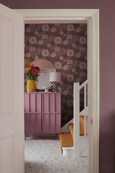 Fluransicht durch eine offene Tür mit Kommode, Spiegel, Lampe, Blumenvase, Tapete, Treppe und Teppich