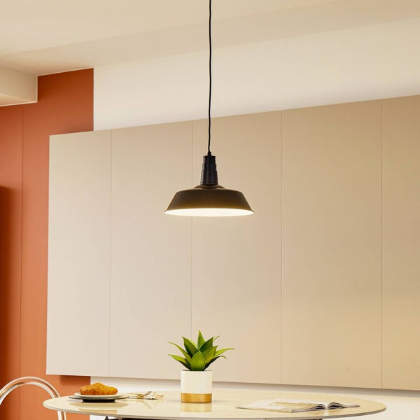 Schwarze Industrie-Pendelleuchte aus Metall über einem runden Esstisch mit Pflanze in einem hellen, modern gestalteten Raum.