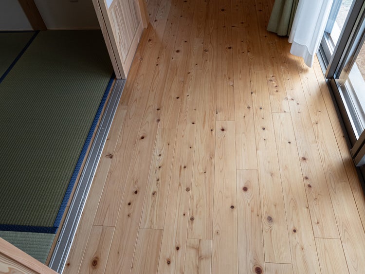 Heller Holzboden aus Massivholz mit sichtbarer Maserung und Ästen in einem hellen Innenraum.