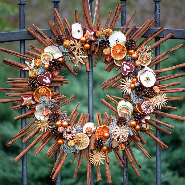 Dekorativer Adventskranz aus Zimtstangen, getrockneten Früchten und Tannenzapfen