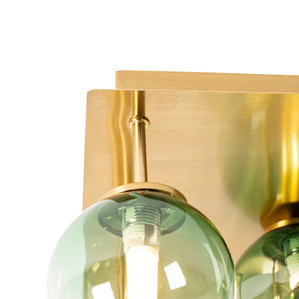 Detailaufnahme einer Wandleuchte mit grünem Glas und Messinghalterung.