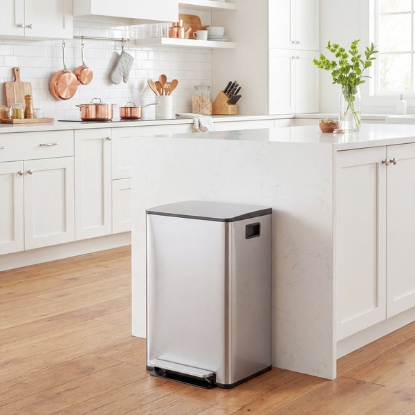 Rechteckiger Treteimer aus Edelstahl in einer hellen, organisierten Küche mit weißen Schränken, Marmor-Arbeitsplatte und Holzboden.