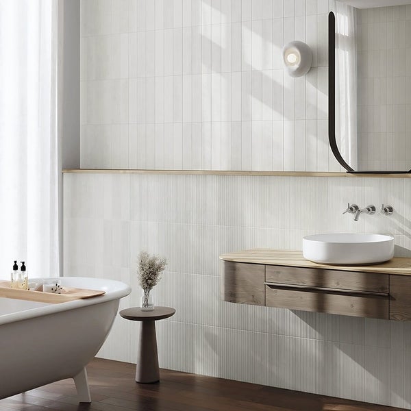 Modernes Badezimmer mit vertikal gefliesten Wänden, freistehender Badewanne, Holzwaschtisch und modernem Aufsatzwaschbecken.