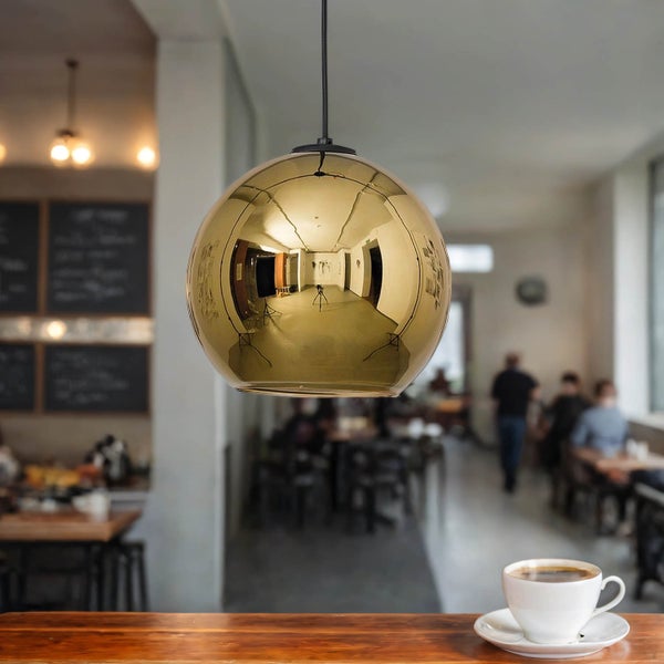 Kugelförmige Pendelleuchte aus Metall über einem Holztisch mit Kaffeetasse in einem Café.