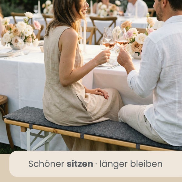 Paar sitzt auf einer Bierbank mit einer grauen Filz Sitzauflage bei einer festlichen Gartenfeier im Freien.