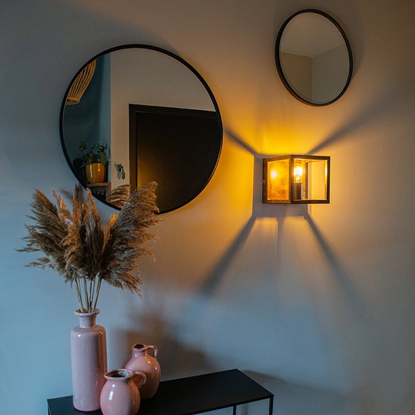 Wanddekoration mit Spiegeln, Wandleuchte und Vasen auf einem Tisch
