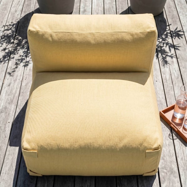 Modulares Outdoor-Sitzmodul aus gelbem Stoff auf einer Holzterrasse für Garten oder Balkon.