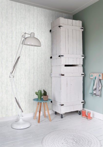 Helle, freundliche Inneneinrichtung mit Stehlampe, Holzkistenstapel und gemusterter Tapete