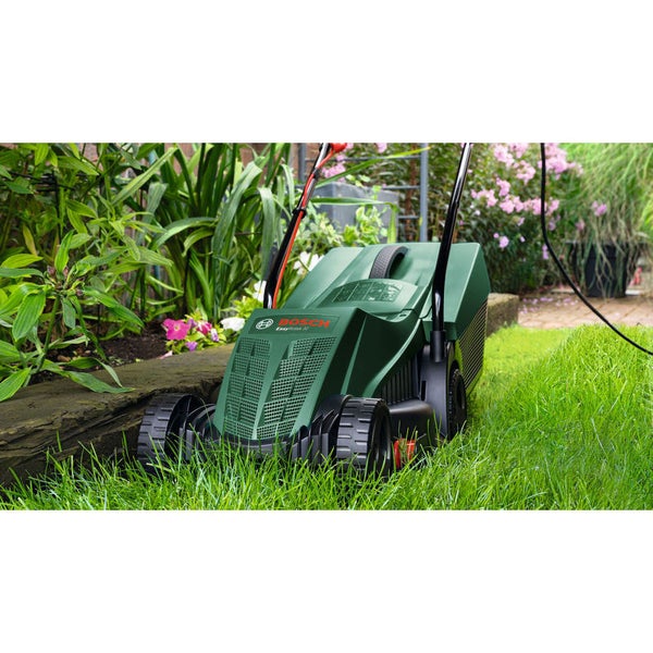 Bosch Rasenmäher beim Mähen von grünem Rasen in einem Garten mit Pflanzen und Blumen.