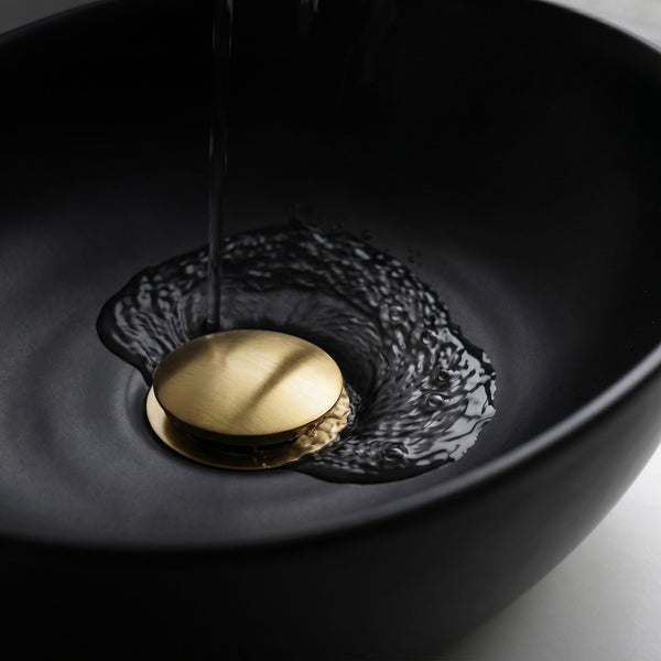 Goldfarbenes Pop-up-Ablaufventil in einem schwarzen Waschbecken mit fließendem Wasser.