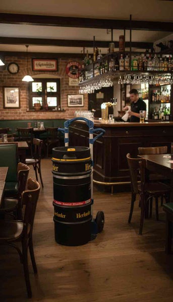 Blick in eine Bar mit Bierfässern auf einem Rollwagen vor dem Tresen.