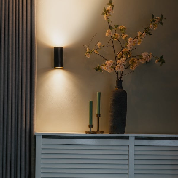 Wandleuchte, Vase mit Blumen und Kerzen auf einem Schrank