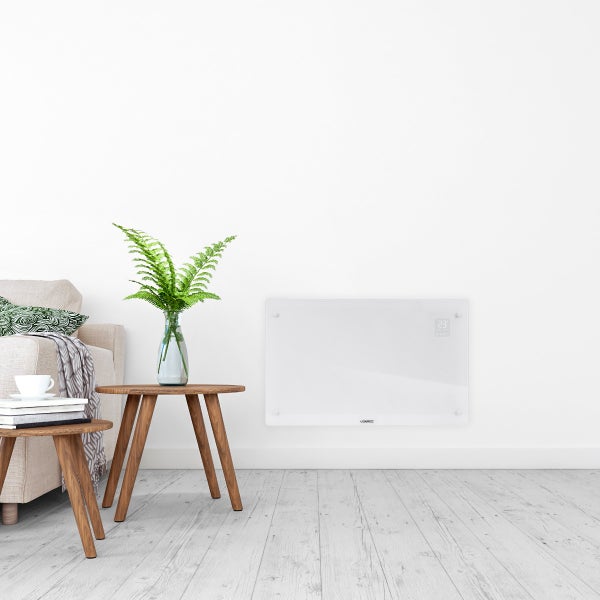Wohnraum mit Sofa, Beistelltischen, Zimmerpflanze und einem an der Wand montierten Heizpaneel