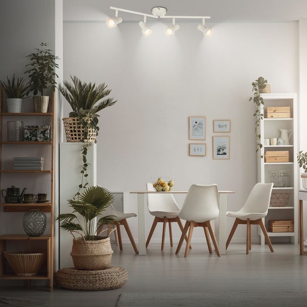 Vierflammige Deckenleuchte mit verstellbaren Spots in einem hellen Esszimmer mit Esstisch, weißen Stühlen und Zimmerpflanzen.