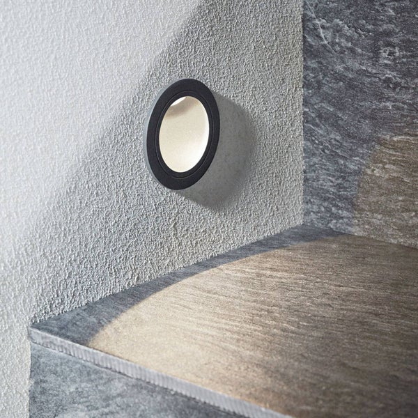 Runde LED-Wandeinbauleuchte zur Treppenbeleuchtung und Wegbeleuchtung, montiert an einer strukturierten Wand über einer Steinstufe.