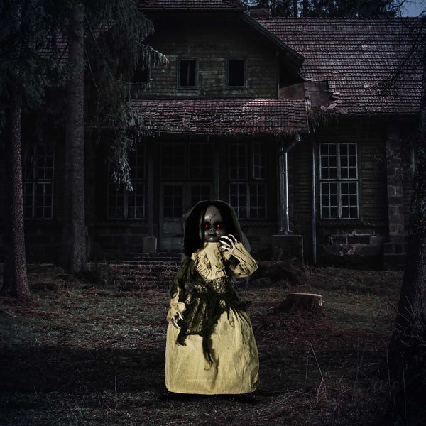 Gruselige Puppe vor einem dunklen, verlassenen Haus als Halloween Dekoration