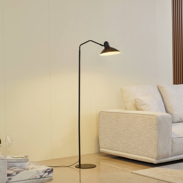 Schwarze Stehlampe neben einem Sofa in einem Wohnzimmer.