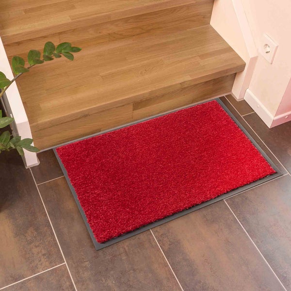 Roter Schmutzfangläufer vor einer Treppe.