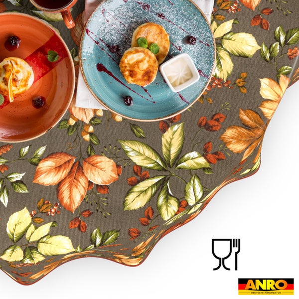 Tischdecke mit Blättermuster auf gedecktem Tisch mit Tellern und Speisen, ANRO Logo, für Lebensmittelkontakt geeignet.