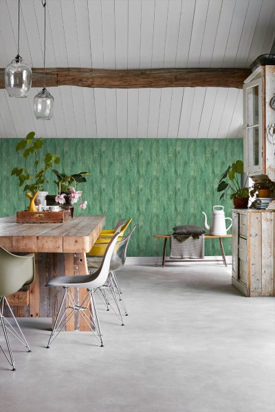 Heller Raum mit Esstisch, Stühlen und grüner Tapete mit Blattmuster.