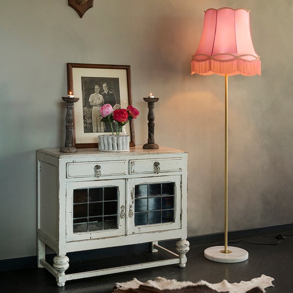 Dekoratives Interieur mit Kommode, Tischleuchte und Wohnaccessoires.