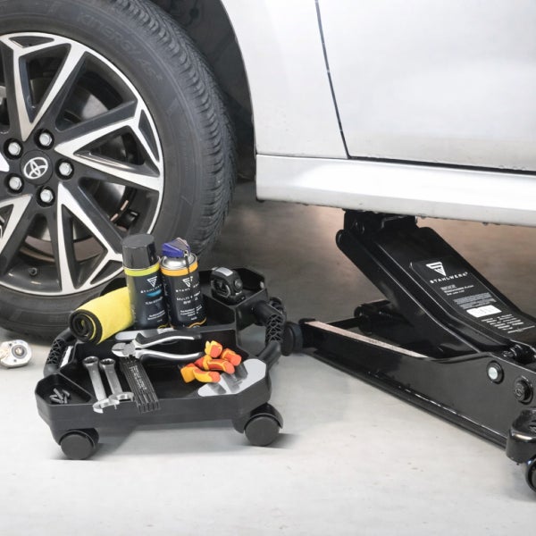 Auto aufgebockt mit Wagenheber, Werkzeugwagen gefüllt mit Werkzeugen und Sprays