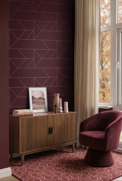 Modernes Wohnzimmer mit geometrischer Vliestapete, Holz-Sideboard und Samtsessel vor einem hellen Fenster.