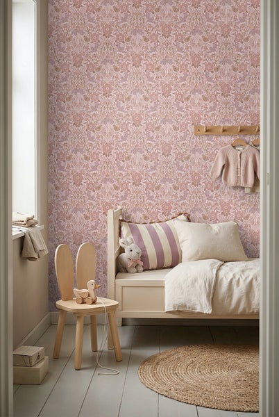Vliestapete mit floralem Vintage-Muster im Kinderzimmer neben einem weißen Bett und einem Holzstuhl mit Hasenohren.
