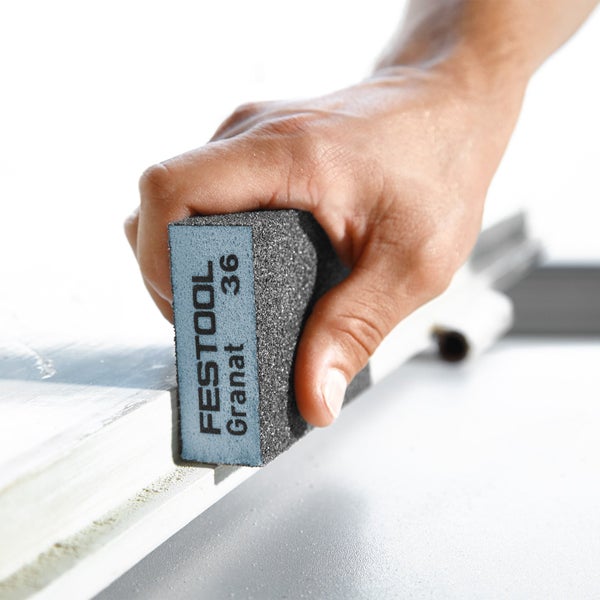 Eine Hand schleift eine Holzoberfläche mit einem Festool Schleifpad Granat 36