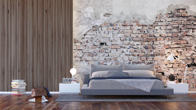 Schlafzimmer mit Bett, Nachttischen, Bücherstapel und Dekor an einer Ziegelwand