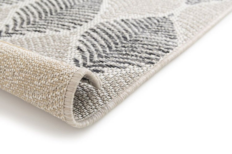 Flachgewebe-Teppich mit Blattmuster und sichtbarer Rückseite an der umgeschlagenen Ecke.