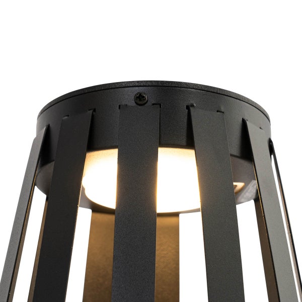 Nahaufnahme einer schwarzen Außenleuchte mit Metalllamellen und leuchtendem runden Lichtelement.