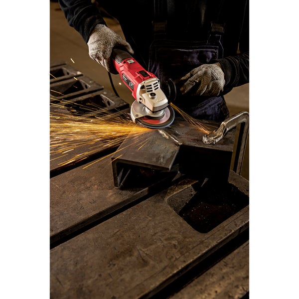 Handwerker schleift Metall mit einem Winkelschleifer und erzeugt Funkenflug in einer Werkstattumgebung.