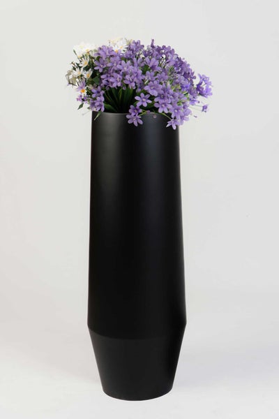 Hohe schwarze Vase mit lila und weißen Blumen.