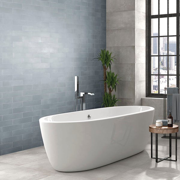 Freistehende Badewanne in einem modern gestalteten Badezimmer mit Wandfliesen im Riemchenformat und großem Fenster.