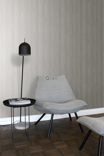 Helles Zimmer mit gemusterter Tapete, Leselampe, Beistelltisch und Sessel mit Fußhocker