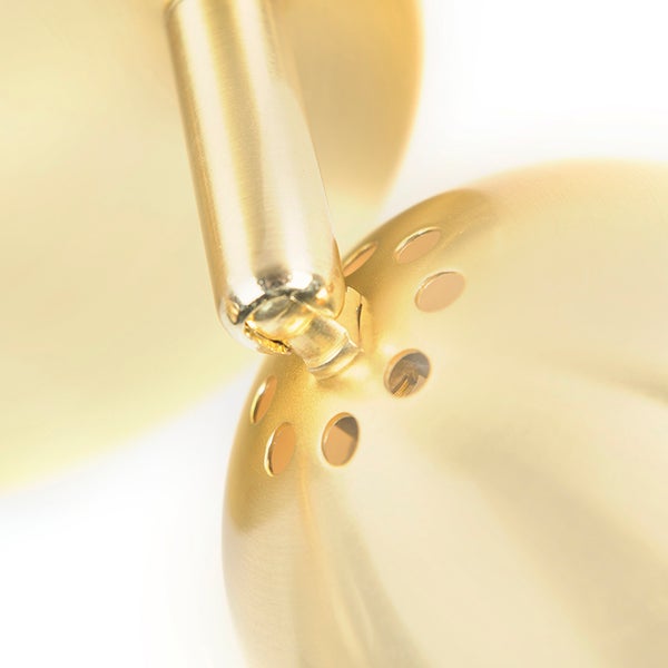 Detailaufnahme einer goldenen Leuchte mit Löchern