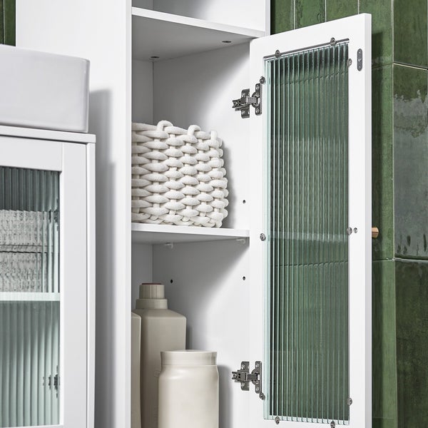 Detailaufnahme eines weißen Badezimmerschranks mit Regalen, einem geflochtenen Korb und gerippten Glastüren