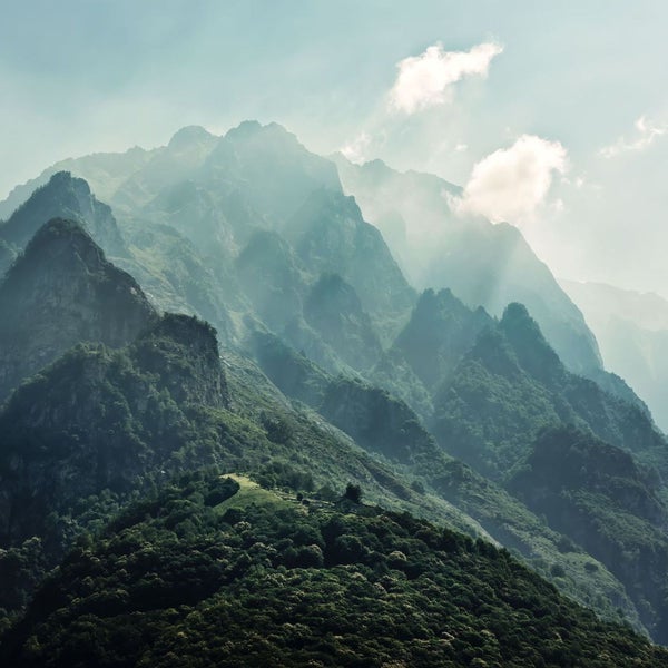 Berglandschaft mit Baumwuchs und Wolken