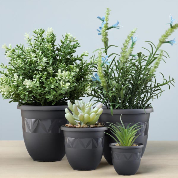 Arrangement aus vier grauen Pflanzgefäßen mit verschiedenen künstlichen Pflanzen.