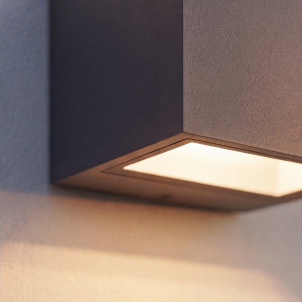 Quadratische Außenwandleuchte mit Lichtaustritt nach unten an einer Hauswand.