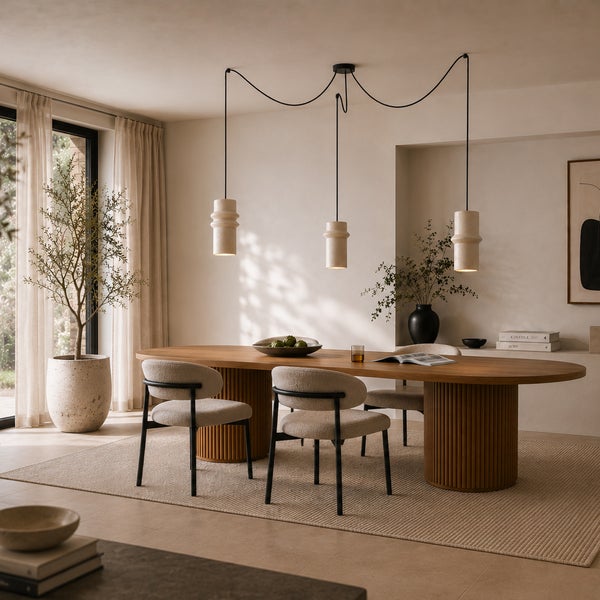 Modernes Esszimmer mit einem ovalen Holztisch mit Lamellenfuß, gepolsterten Stühlen und drei hängenden Pendelleuchten in einem hellen Raum.