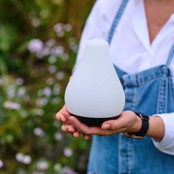 Weiße LED-Gartenleuchte wird von einer Person im Garten gehalten.