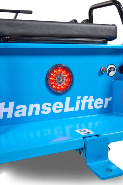 Detailansicht eines blauen HanseLifter Fahrzeugs mit rotem LED Rücklicht, weißem Markenschriftzug und schwarzer Sitzfläche.